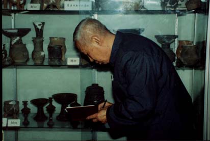 1991年10月13日佟柱臣先生在山东章丘城子崖文物标本室研究陶器